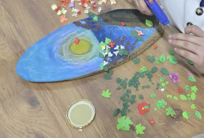 Kil çiçeklerle süslenen ahşap pano, atölye masasında